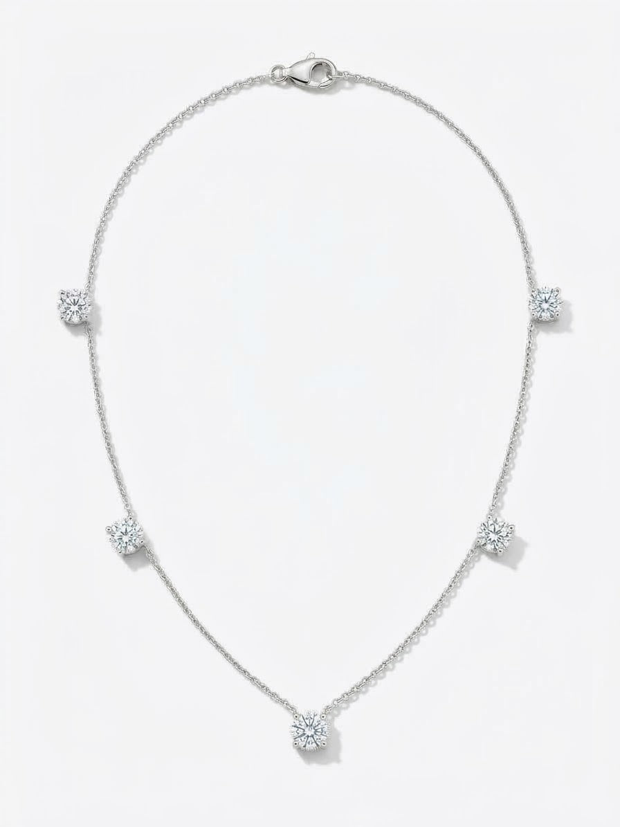 A delicate white gold  chain necklace featuring five small, round-cut clear gemstones spaced evenly along the chain.The necklace is displayed on a clean white background 