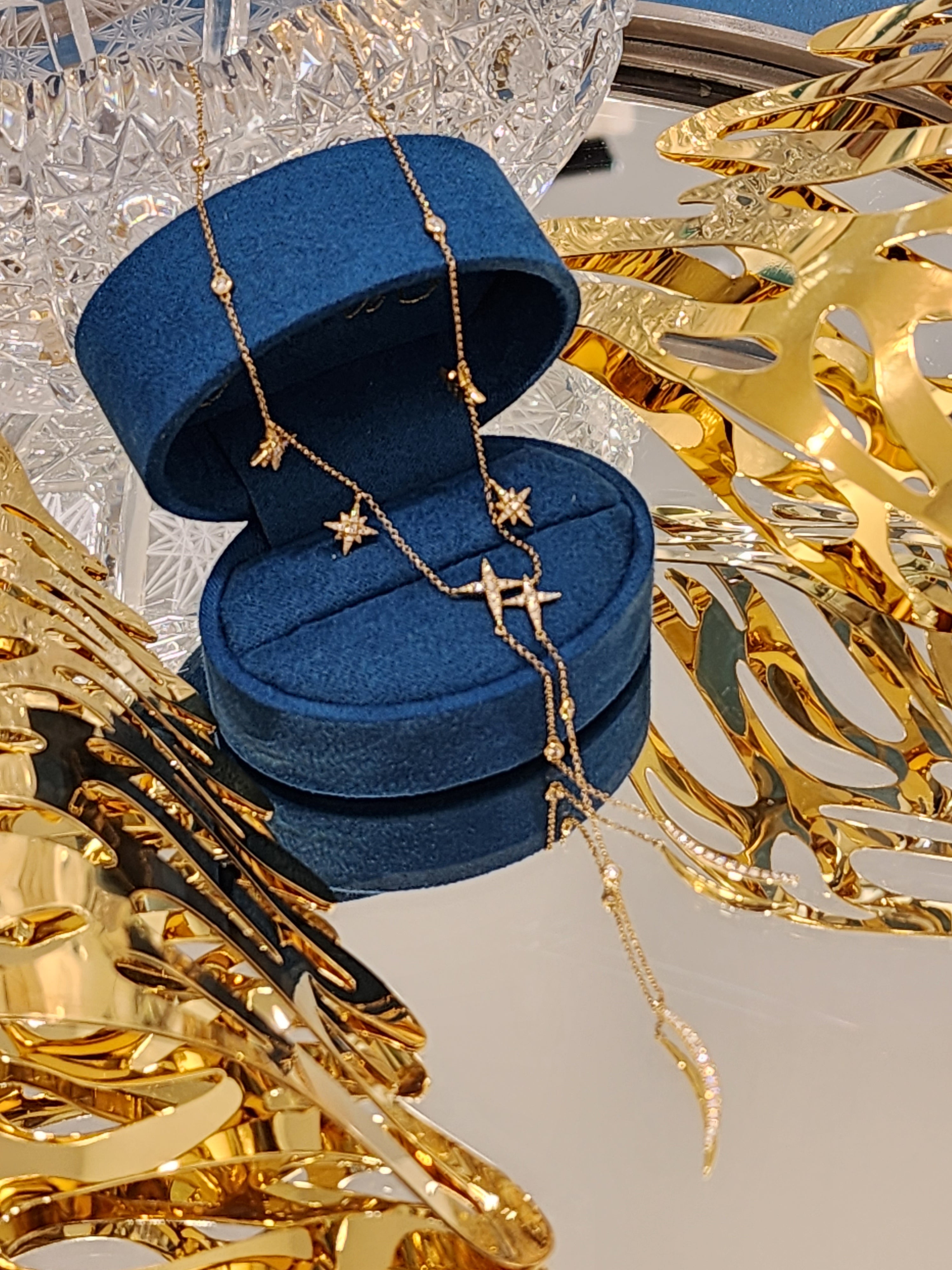 Blue jewelry box with gold chains on a decorative background